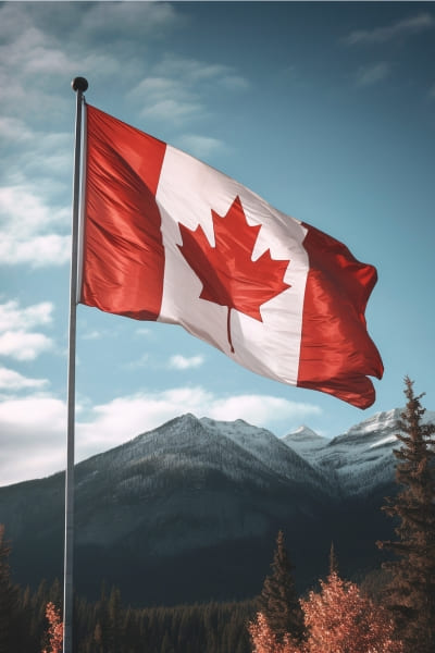 Bandeira do canada hasteada com montanhas canadenses e vegetação ao fundo. A Santy ajuda você com seu Visto Canadense.
